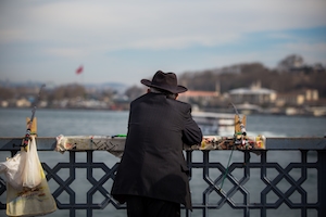 Мужчина в шляпе на мосту смотрит на панораму Стамбула
