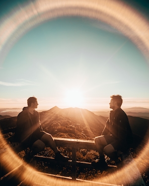 два парня на фоне заката в горах, красочное солнце и небо