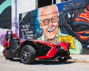 супергеройский автомобиль красного цвета на фоне стены с граффити 