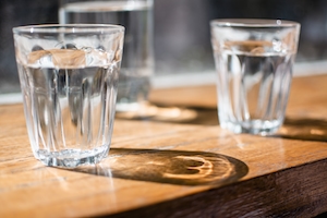 вода в прозрачных стеклянных стаканах, стоящих на деревянном столе, крупный план 