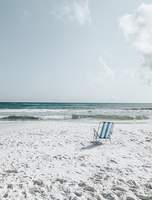пляж, голубая вода, голубое небо, белый песок и один полосатый лежак 