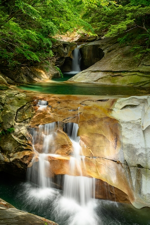 водопад на замшелых камнях, отвесные скалы 