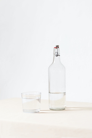 предметная съемка, крупный план, прозрачная бутылка воды и стакан с водой 