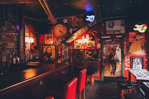 Ирландский паб, наполненный памятными вещами и плакатами, покрывающими стены, и красным свечением