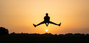 Силуэт человека в прыжке на фоне заката, красочное солнце и небо