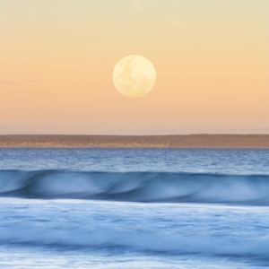 Почти полная луна во время заката над морем 