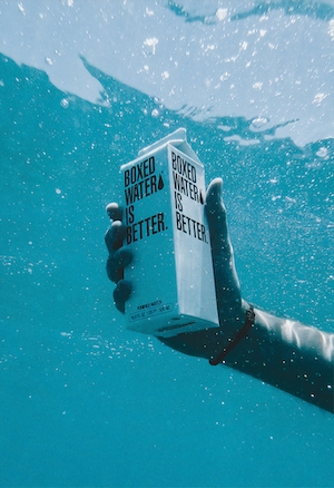 белая коробка с водой в море под водой в руке человека 
