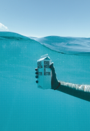 белая коробка с водой в море под водой в руке человека 