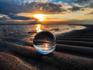 Хрустальный шар в песке на берегу Балтийского моря на закате