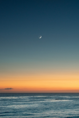 полумесяц на небе во время заката над морем 