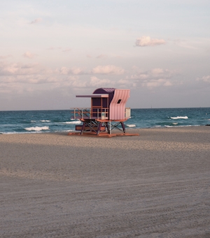 Розовая башня спасателя, песчаный пляж и голубое море 