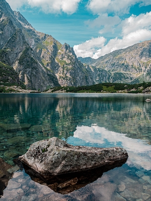 Горное озеро, отражение неба и гор в воде, лесу у озера и гор, большие камни и прозрачная вода 