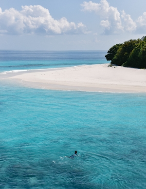 остров в бирюзовом море, белый песок и пальмы, человек плавает в бирюзовой воде 