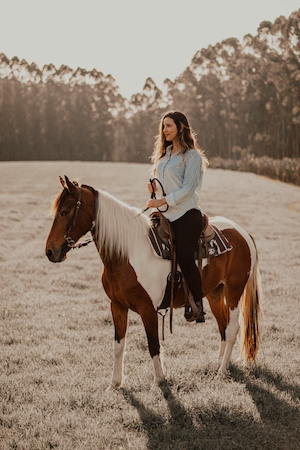 девушка сидит верхом на коричневой лошади с белоснежной гривой 