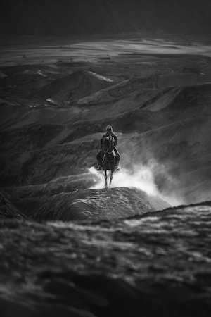 лошадь с наездником идут по песчаным склонам, черно-белая фотография 