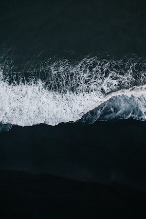 Черный пляж Вика, морская волна на черном пляже, кадр сверху 