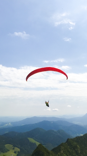 человек летит с парашютом в горной долине 