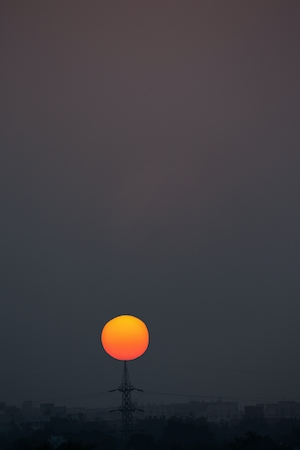 оранжевое закатное солнце на сером небе 