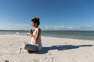 девушка медитирует на пляже 