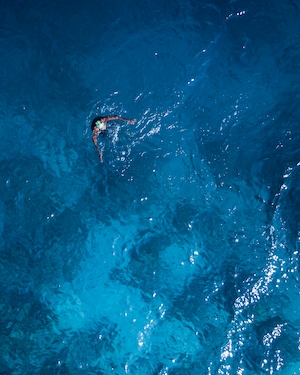 Купание в океане, человек купается в синей воде 