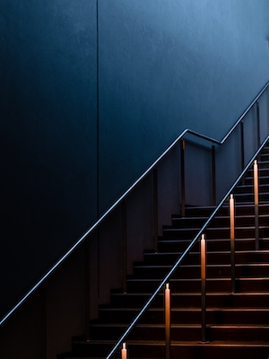 Темная лестница у черной стены с металлическими перилами 