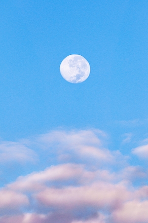 полная луна на голубом небе во время заката в окружении облаков 