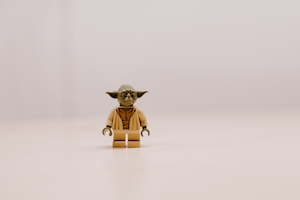 Лего Йода сидит на светлой поверхности, игрушка лего 