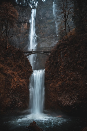 отвесный водопад посреди высоких отвесных скал, бассейн, мост над водопадом 