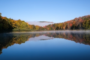 Ранним утром осенний пейзаж с туманом. Вид на туманное озеро в Онтарио. Природные пейзажи, осень, деревья, туман, озеро, отражение в воде, голубое небо, туманная, красивая листва. Лес у озера, отражение леса в воде озера, озеро днем