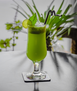 Зеленый лимонный сок в бокале с трубочкой