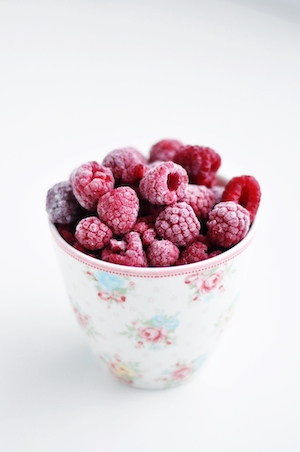 Замороженные ягоды в стакане на белом фоне