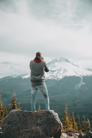 человек фотографирует горы, кадр со спины 