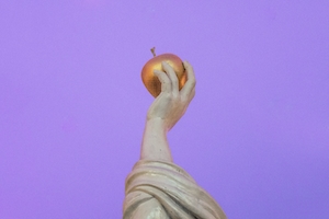 Яблоко в руке у богини на фиолетовом фоне