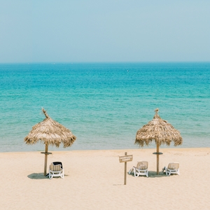 летний пляж, пляж, голубая вода, голубое небо, лежаки с соломенными зонтиками 