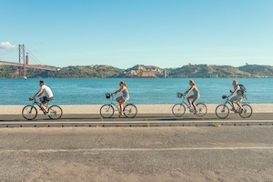 велосипедисты проезжают мимо пляжа в Лиссабоне