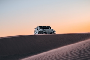 Белый джип Wrangler на песчаных дюнах в пустыне Южной Калифорнии сразу после захода солнца.