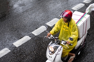 Мотоциклист на мокрой дороге в Бангкоке, Таиланд.