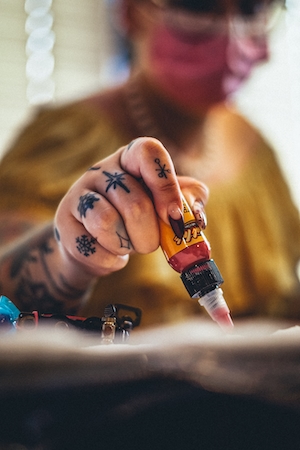 татуировщик мешает краску для тату 