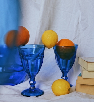 цитрусовые, ярко-синие бокалы и стопка книг, натюрморт