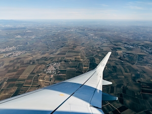 Фото крыла самолета из окна иллюминатора, поля 