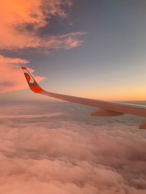 Фото крыла самолета из окна иллюминатора во время заката 