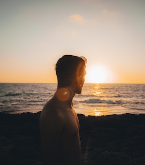 Силуэт человека на фоне заката над морем, красочное солнце и небо