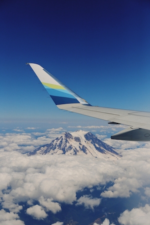 Фото крыла самолета из окна иллюминатора, гора и облака 