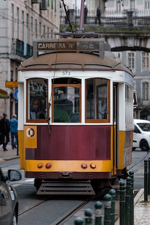 Старый португальский трамвай на дороге с людьми, едущими на работу 