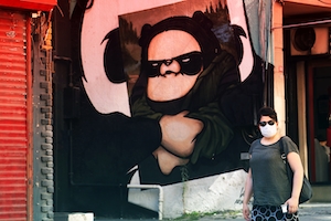 женщина в маске на фоне граффити 