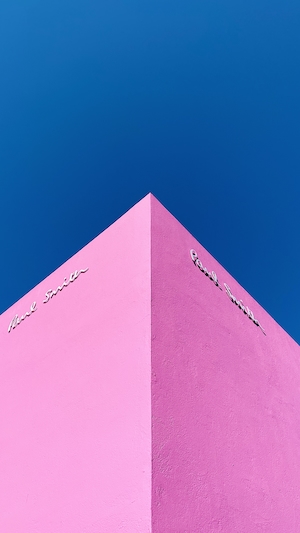 розовый угол здания на фоне синего неба 