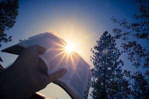 рука человека с книгой на фоне закатного неба