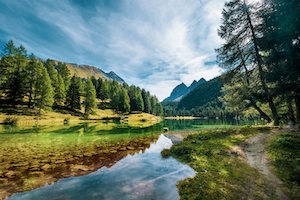 Горный пейзаж с озером в Швейцарии. Горное озеро, отражение неба и гор в воде, лесу у озера и гор 