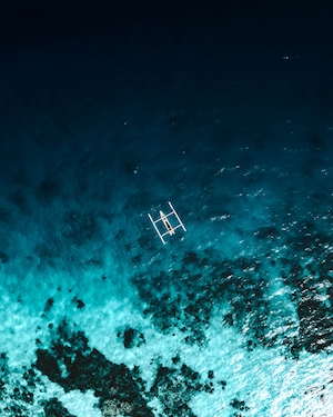 фото прибрежной полосы со скалистым берегом, катер в прозрачном море