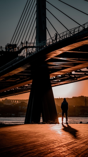 Человек стоит под мостом через пролив 
